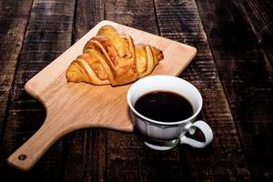 café da manhã café e croissant na mesa de madeira isolada. foto