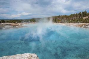 vista da erupção do gêiser excelsior na floresta no parque nacional de yellowstone foto