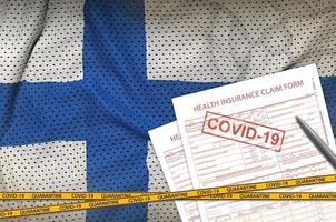 bandeira finlandesa e formulário de solicitação de seguro de saúde com carimbo covid-19. conceito de vírus coronavírus ou 2019-ncov foto