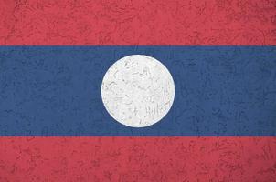 bandeira do laos retratada em cores brilhantes de tinta na parede de reboco em relevo antigo. banner texturizado em fundo áspero foto