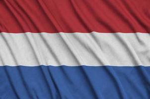 A bandeira da Holanda é retratada em um tecido esportivo com muitas dobras. bandeira da equipe esportiva foto