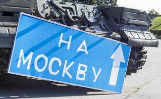 sinal de estrada azul com letras brancas perto do tanque, no território do museu nacional da história da ucrânia. guerra da rússia contra a ucrânia. tradução, para moscou. foto