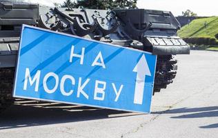 sinal de estrada azul com letras brancas perto do tanque, no território do museu nacional da história da ucrânia. guerra da rússia contra a ucrânia. tradução, para moscou. foto