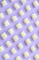 marshmallow colorido disposto em fundo de papel violeta. padrão texturizado criativo pastel. mínimo foto