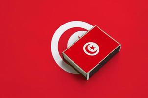 a bandeira da tunísia é retratada em uma caixa de fósforos que fica em uma grande bandeira foto