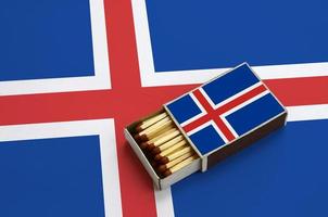 A bandeira da Islândia é mostrada em uma caixa de fósforos aberta, que está cheia de fósforos e fica em uma grande bandeira foto