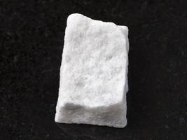 pedaço de pedra de mármore branco áspero no escuro foto