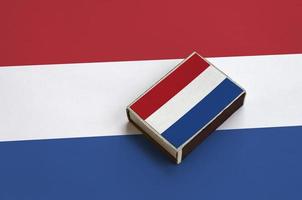 bandeira holandesa é retratada em uma caixa de fósforos que fica em uma grande bandeira foto