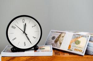 despertador branco colocado em dólar de prata e conceito de finanças simplificado de tempo foto