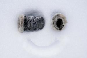 carinha engraçada caseira, com luvas em vez de olhos e um sorriso pintado na neve. ideia criativa. vista do topo. foto