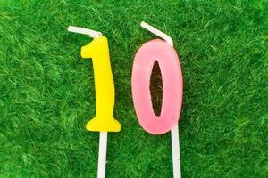 vela na forma de número 10 no fundo da grama verde, um lugar para um texto de saudação foto