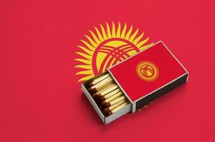 A bandeira do Quirguistão é mostrada em uma caixa de fósforos aberta, cheia de fósforos e em uma grande bandeira foto