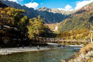 prazer de turistas não identificados na ponte kappa bashi na área do ponto central do parque nacional de kamikochi, nagano, japão durante a temporada de folhagem de outono. foto