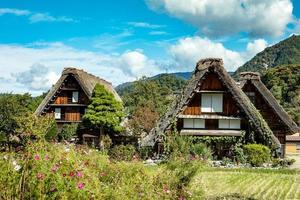 vila japonesa de shirakawago durante outubro na temporada de folhagem de outono. casa tradicional de shirakawa no telhado triangular com fundo de campo de arroz, montanha de pinheiros e céu de nuvens claras depois. foto