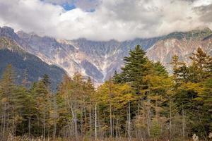 belo plano de fundo do centro do parque nacional de kamikochi por montanhas de neve, rochas e rios azusa de colinas cobertas foto