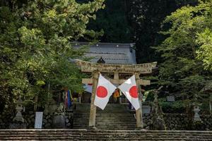 shirakawago, gifu, japão - outubro de 2022 - área do portão do santuário shirakawa hachiman na vila de shirakawago com pinheiros e bandeira japonesa. foto