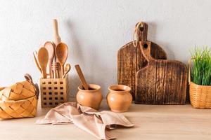 fundo de cozinha da cozinha moderna urbana. bancada de madeira com itens ecologicamente corretos, utensílios, tábuas de madeira, panelas de barro. foto