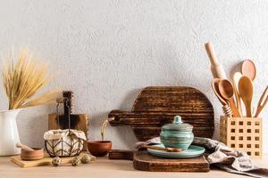 um conjunto de tábua caseira de madeira no interior de uma cozinha moderna de uma casa de campo, vila. bancada de madeira com utensílios de cozinha. foto