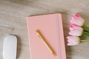 mesa de escritório em casa das mulheres. espaço de trabalho com flores de tulipa rosa, notebook. flatlay, vista superior. composição de blog de moda. foto