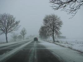 inverno, neve, nevasca, pouca visibilidade na estrada. carro durante uma nevasca na estrada foto