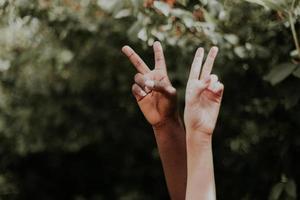 duas pessoas multiétnicas mostrando um símbolo da paz