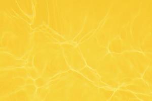 desfocar textura de superfície de água calma transparente de cor amarela transparente turva com splashe e bolha. fundo de natureza abstrata na moda. ondas de água à luz do sol com espaço de cópia. brilho aquarela amarelo foto