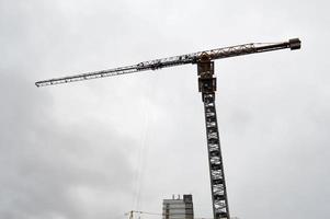 grande guindaste industrial de carga de construção poderoso em um canteiro de obras de novos edifícios e casas contra o céu foto