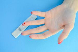 exame de sangue para o diagnóstico de coronavírus. uma garota com uma manicure vermelha brilhante tem uma gota de sangue no dedo anelar. punção do dedo da lanceta, teste rápido em casa foto