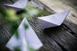 origami, barco de papel branco isolado em um piso de madeira. barquinhos de papel significam andar. sentimento de liberdade liderança foto