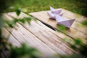 origami, barco de papel branco isolado em um piso de madeira. barquinhos de papel significam andar. sentimento de liberdade liderança foto