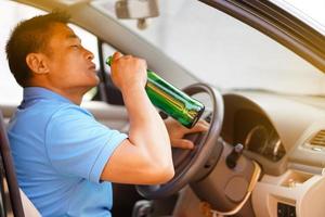 homem bêbado asiático detém garrafa de cerveja para beber no carro. conceito, pare de dirigir enquanto bebe álcool ou campanha de uísque. ilegal e perigoso para dirigir veículo que leva a acidente. foto