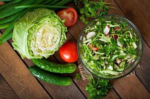 salada saudável dietética de legumes frescos em uma tigela de vidro em um fundo de madeira. foto