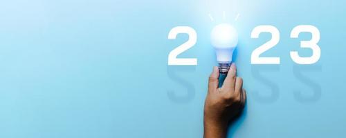 ideia e criativo em 2023, lâmpada de iluminação com número de ano novo em fundo azul