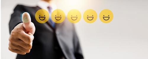 avaliação e feedback de revisão, o melhor e excelente admirado pelo revisor, close-up no polegar para cima do empresário com rostos de emojis dourados foto