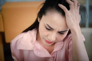 jovem mulher asiática que sofre de dor de cabeça no local de trabalho. foto