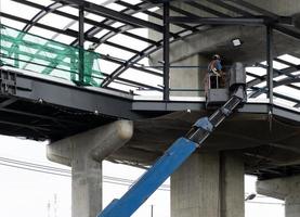 o engenheiro na caçamba do veículo guindaste para verificar a estrutura metálica. foto