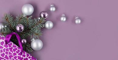 o conceito de um fundo de natal. vista superior de bolas de prata de uma caixa de presente de natal com ramos de abeto em um fundo roxo elegante. foto