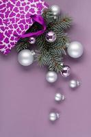 o conceito de um fundo de natal. vista superior de bolas de prata de uma caixa de presente de natal com ramos de abeto em um fundo roxo elegante. foto