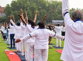 sessão de exercícios de ioga em grupo para pessoas de diferentes faixas etárias no estádio de críquete em delhi no dia internacional da ioga, grande grupo de adultos participando da sessão de ioga foto