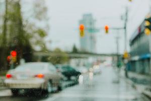 carros desfocados em um semáforo em um dia chuvoso