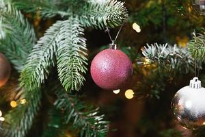 Natal clássico ano novo decorado árvore de ano novo com enfeites de prata rosa brinquedo e bola e luzes de guirlanda desfocadas. design de férias clássico moderno. véspera de natal em casa. foto