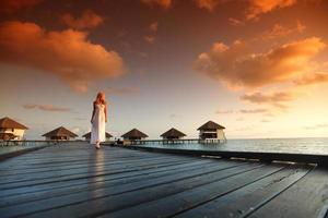 mulher em um vestido no pôr do sol maldivo foto