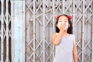 garotinha asiática bocejando com máscara foto
