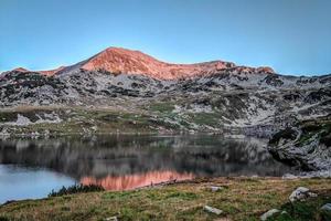 nascer do sol no pico de uma montanha perto de um lago foto