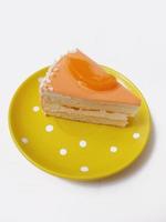 um pedaço de bolo em um prato amarelo sobre um fundo branco foto