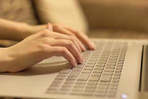 mulher trabalhando em home office, mãos no teclado do laptop. fechar-se foto