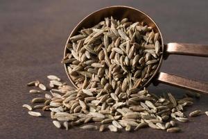 sementes de cominho derramadas de uma colher de chá foto