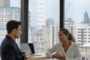 duas pessoas corporativas de diversidade têm negócios discutindo no espaço de trabalho do escritório moderno com fundo de céu azul da cidade. foto