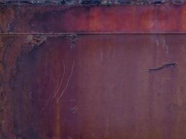 a superfície áspera da placa de aço enferrujada está manchada, vermelho-alaranjada, riscada como fundo. foto