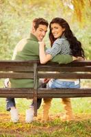 jovem casal sorridente em um banco de parque foto